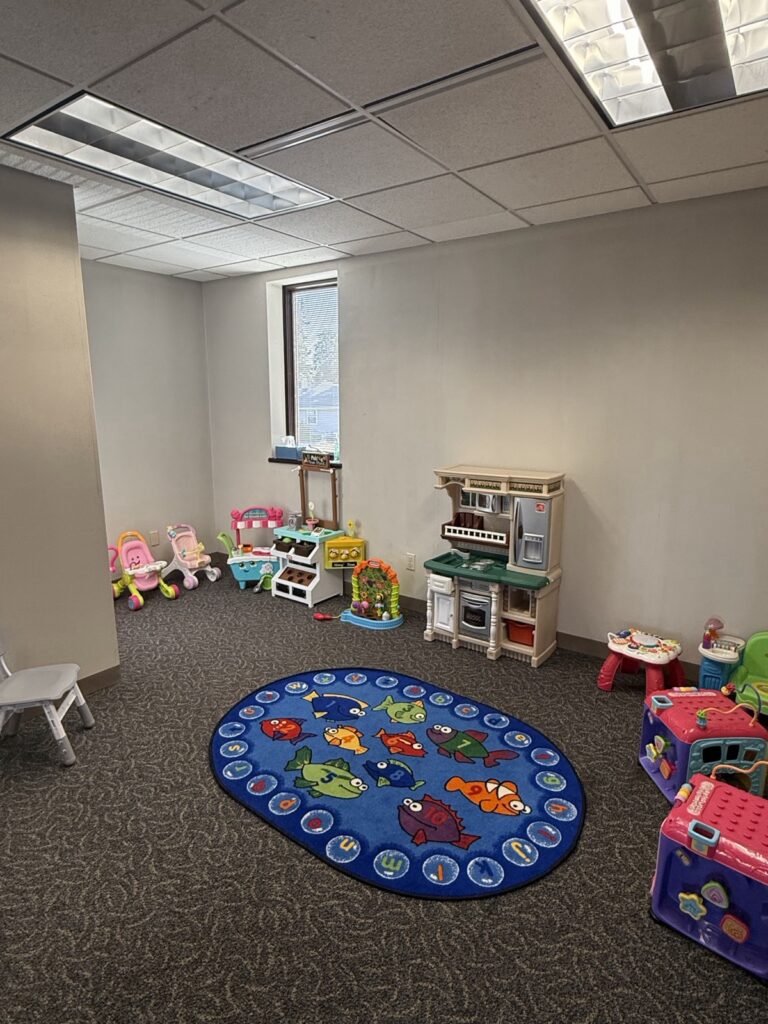 Play room with a toy kitchen, ride-on toys and an ocean-themed rug